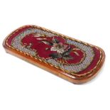 A Victorian mahogany stand, of oval form, inset with a bead work panel depicting flowers, on four bu