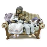 A Lladro Porcelain figure group, of two girls and a puppy seated on a sofa, one reading a book, numb