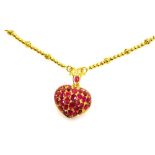 A heart shaped ruby set pendant on heavy bead necklace, the pierced heart locket set with variously
