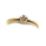 A solitaire diamond ring, the stone of 2.5mm diameter, in rub over setting to yellow metal shank, si