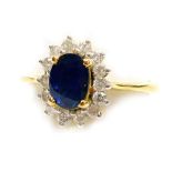 A sapphire and diamond set dress ring, the central faceted oval sapphire of 6.2mm x 5mm, surrounded