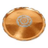 An Arts & Crafts beaten copper and pewter circular tray, decorated centrally with a rose, PG stamp m