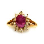 A ruby and diamond set cluster dress ring, the central oval faceted ruby of 6.1mm x 5.2mm surrounded