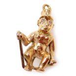 A 9ct pendant cast as a monkey, wearing a top hat and holding a walking cane, with diamond set eyes,