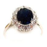 A sapphire and diamond ring, the oval cut sapphire basket set in a surround of twelve diamonds, in a