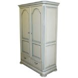 A cream and pale blue painted pine double wardrobe, the outswept pediment over a pair of doors enclo