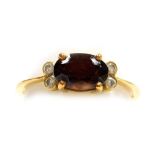 A stone set dress ring, a central oval brown/orange faceted stone, 7mm x 5mm, with a pair of tiny di