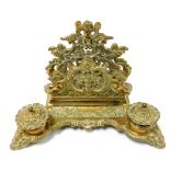 A Victorian brass desk stand, embossed with cherubs, winged creatures and cornucopia, with a single