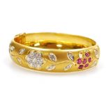 A ruby, diamond and sapphire set bloomed gold hinged bangle, of floral form, a ruby set flower head