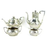 An Edward VII silver four piece tea service, with part fluted body and urn finial, with acanthus lea