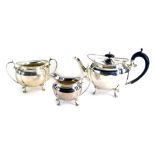 A George V silver three piece tea service, with an ebonised handle and knop, on fluted design, Sheff