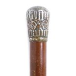 An early 20thC stained pine walking cane, with a plated handle, embossed with flowers, 88cm high.
