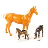 Three Beswick horses, comprising a large tan horse, 22cm high, and two brown foals. (3)