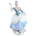A Royal Dux porcelain figure of a lady, in blue and white spotted dress, picked out in gilt with pin