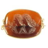 A late 19thC brooch, of oval form, with central amber stone depicting two maiden heads, in a gold co