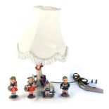 A group of Goebel by Hummel figures, comprising a table lamp of a child on tree trunk with dog, with