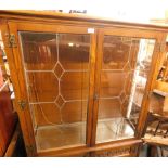 An oak two door display cabinet, with glazed panel top, with three shelves, above two cupboard doors