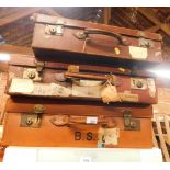Three leather bound trunks, of varying sizes, one bearing label for Paddington and Torquay Stations.