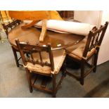 An oak circular extendable kitchen table, and four associated chairs. (5) The upholstery in this lot