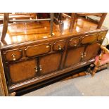 A 1950's oak sideboard, with moulded cornice back, with arrangement of single drawers and two cupboa