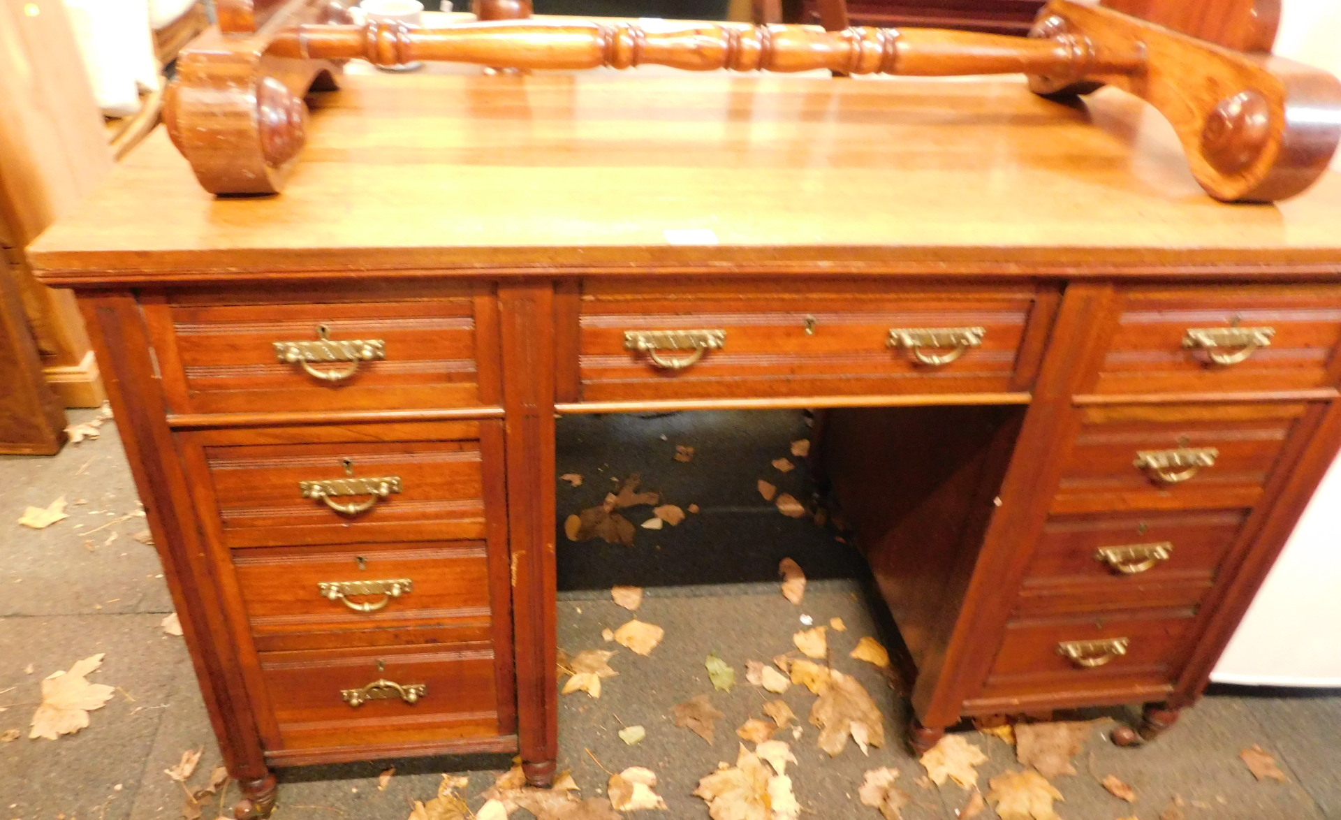 An Edwardian oak writing desk, with arrangement of four drawer pedestals and single central door, on