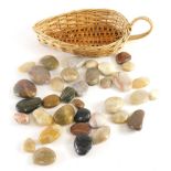 Various polished stones, onyx type and others, contained in a wicker leaf shaped basket, 30cm long.