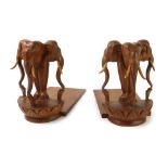 A pair of carved wooden tribal bookends, with triple elephant heads to each end, 20cm high. (2)