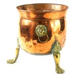An early 20thC copper and brass planter, with bell shaped bowl, flanked by lions mask handles, on ac