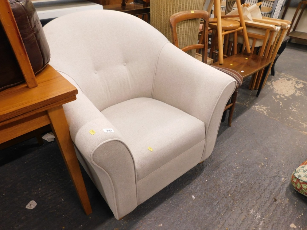 A beige upholstered tub shaped armchair on plain beech feet.