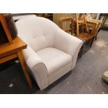 A beige upholstered tub shaped armchair on plain beech feet.