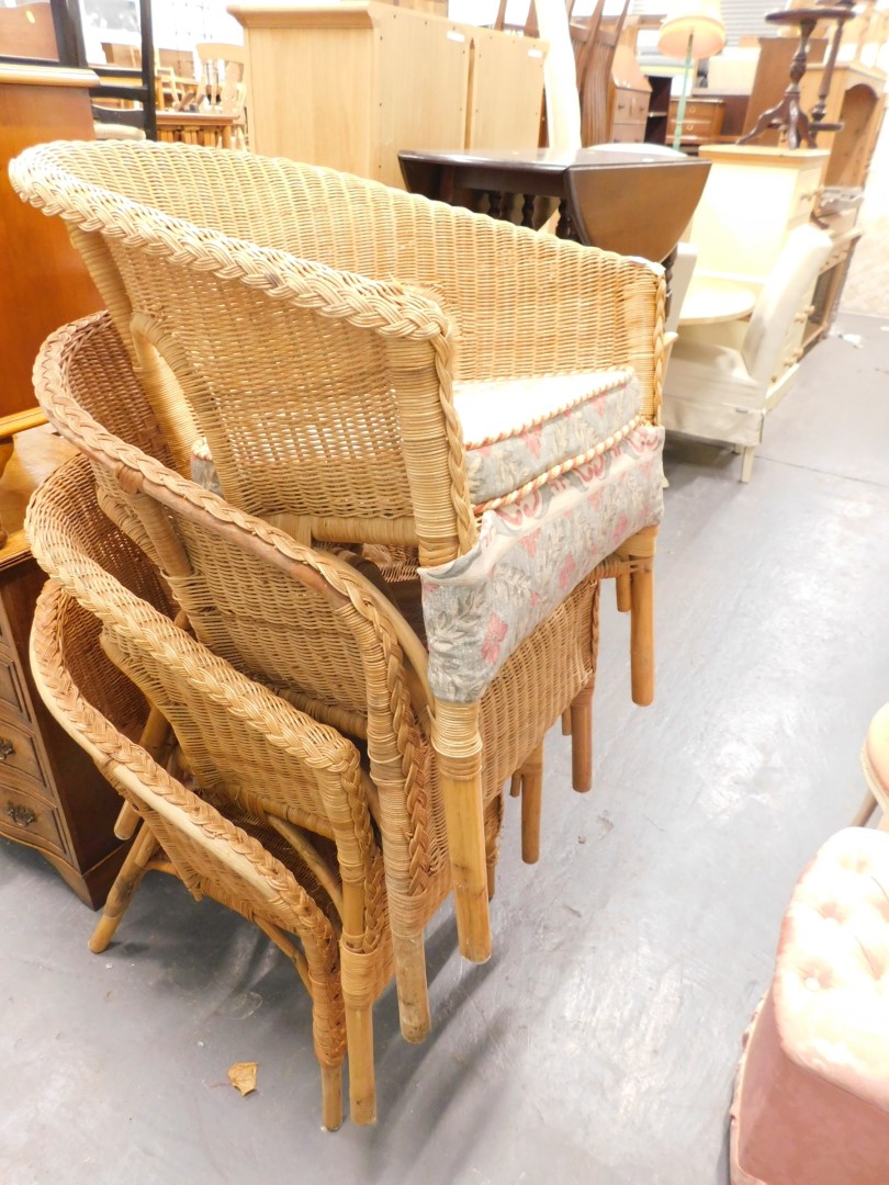 A set of four basket woven Lloyd Loom style tub chairs each with turned legs.