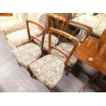 Four Edwardian dining chairs with overstuffed seats in floral materials, on turned front legs.