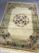 Cream ground woollen rug with green border ad pink/blue design, approx 200cm x 135cm