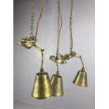 Three decorative brass pendant lights with brass shades held by flying cherubs