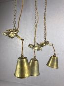 Three decorative brass pendant lights with brass shades held by flying cherubs