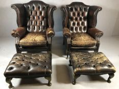 Pair of leather upholstered wingback fireside armchairs with button backs and matching foot