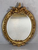 Ornate wooden gilt framed bevel edged oval mirror, approx 110cm x 76cm