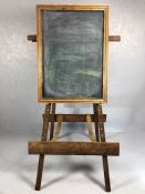 Large wooden vintage easel with fabric straps and supporting a wooden framed blackboard, total