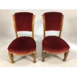 Pair of carved light wood low bedroom chairs with red velvet seats and backs