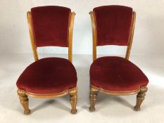 Pair of carved light wood low bedroom chairs with red velvet seats and backs