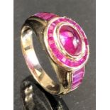 9ct Gold ring set with a cabochon rubywith a halo of Gemstones and square cut gemstones to