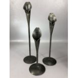 Set of three graduating metal candlesticks in the form of Lillies