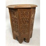 Small octagonal carved wooden tea table with hinged folding base and floral design, approx 57cm in