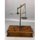 Pair of De Grave Short & Co brass scales on stained rectangular wooden base, with pendulum-style