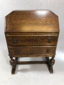 Oak bureau with fall front revealing leather writing desk, two drawers, on carved legs
