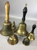 Collection of five brass hand bells, two possibly Indian, three with turned wooden handles, of