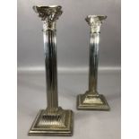 Pair of silver coloured Corinthian column candlesticks on square stepped bases, stamped 'Made in