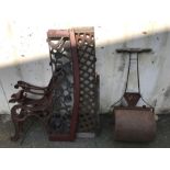 Vintage garden items: a garden roller and a cast iron bench in need of restoration