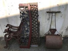 Vintage garden items: a garden roller and a cast iron bench in need of restoration