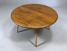 Blond Ercol circular coffee table on four turned legs with blue Ercol badge, approx 74cm in diameter